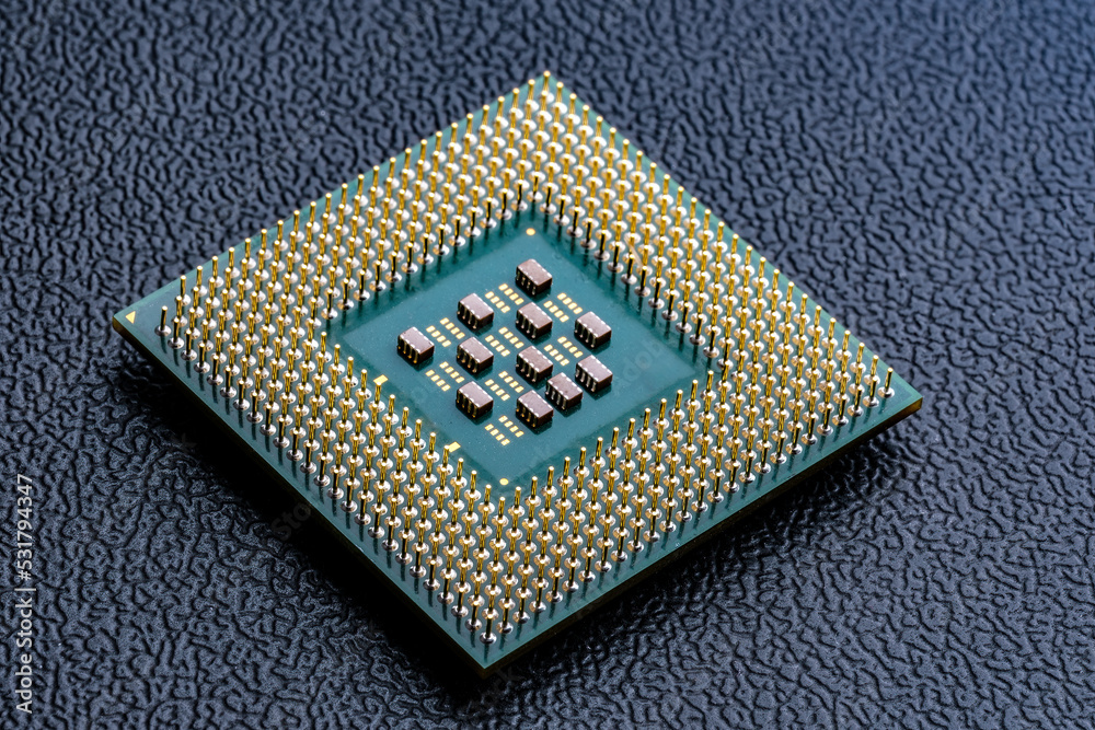 Large computer chip CPU with hundreds of gold pins and tiny components - capacitors, resistors on its board. Concept for microchips and semiconductor inducstry. Selective focus. Large computer chip CPU with hundreds of gold pins and tiny components - capacitors, resistors on its board. Concept for microchips and semiconductor inducstry. Selective focus.