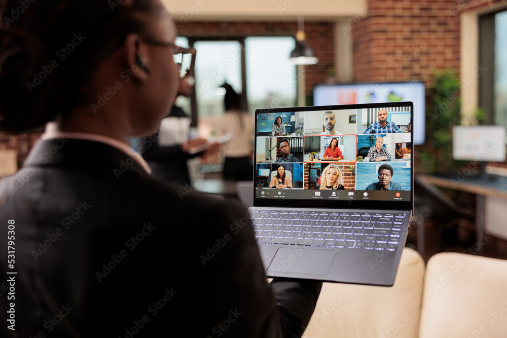 Company worker attending business meeting on remote videocall, using laptop and webcam to talk to colleagues on online teleconference chat. Talking on videoconference call for telecommunications. Company worker attending business meeting on remote videocall, using laptop and webcam to talk to colleagues on online teleconference chat. Talking on videoconference call for telecommunications.