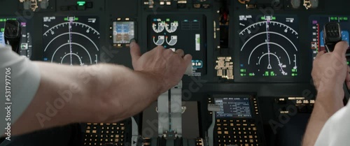 DOLLY IN Commercial aircraft pilots controlling airplane throttle lever during the flight or take off. View from inside the cabin. Real aircraft, daytime shot