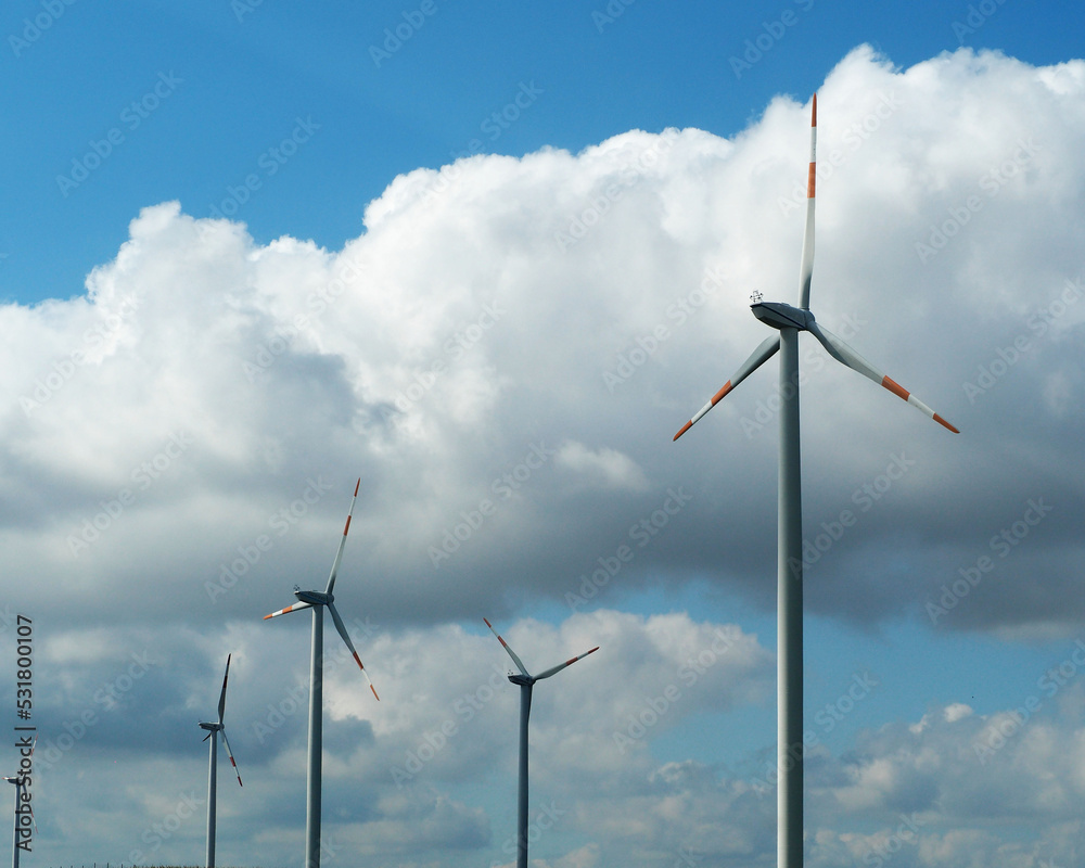 there are a lot of wind turbines on the background of a blue sky with white clouds. electricity production . electricity production. ecology there are a lot of wind turbines on the background of a blue sky with white clouds. electricity production . electricity production. ecology