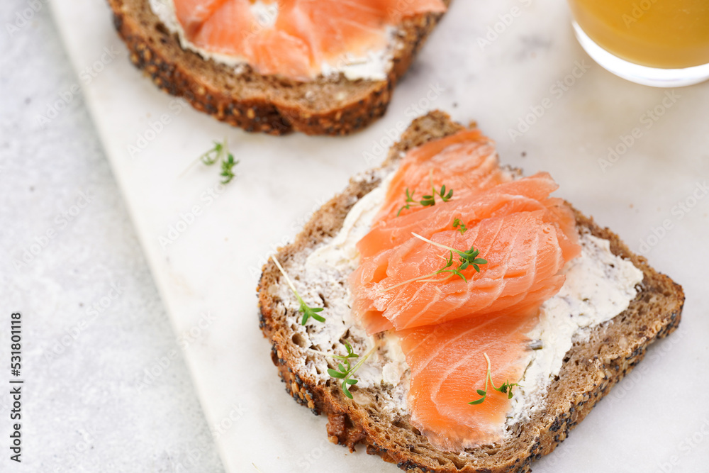 Wholewheat bread sandwiches with cream cheese and smoked salmon on marble board with lime slices and sour cream Wholewheat bread sandwiches with cream cheese and smoked salmon on marble board with lime slices and sour cream