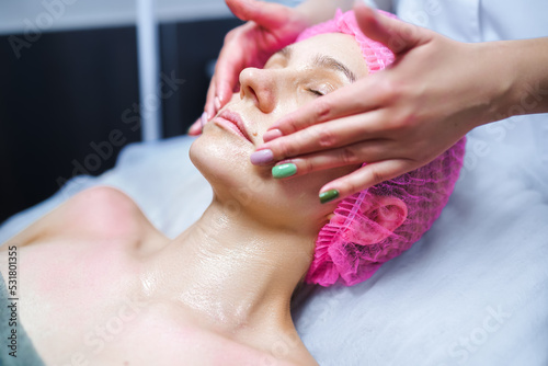 Attractive female at spa health club getting a facial massage. Beautician doing massage of face  neck and shoulders ofbeautiful young woman at luxury beauty salon