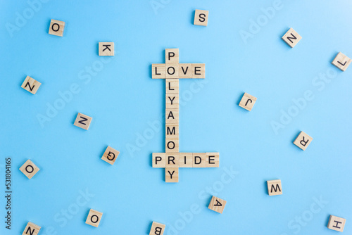 Word Polyamory, Love and Pride on wooden blocks on blue background. Polyamorous relationship concept photo