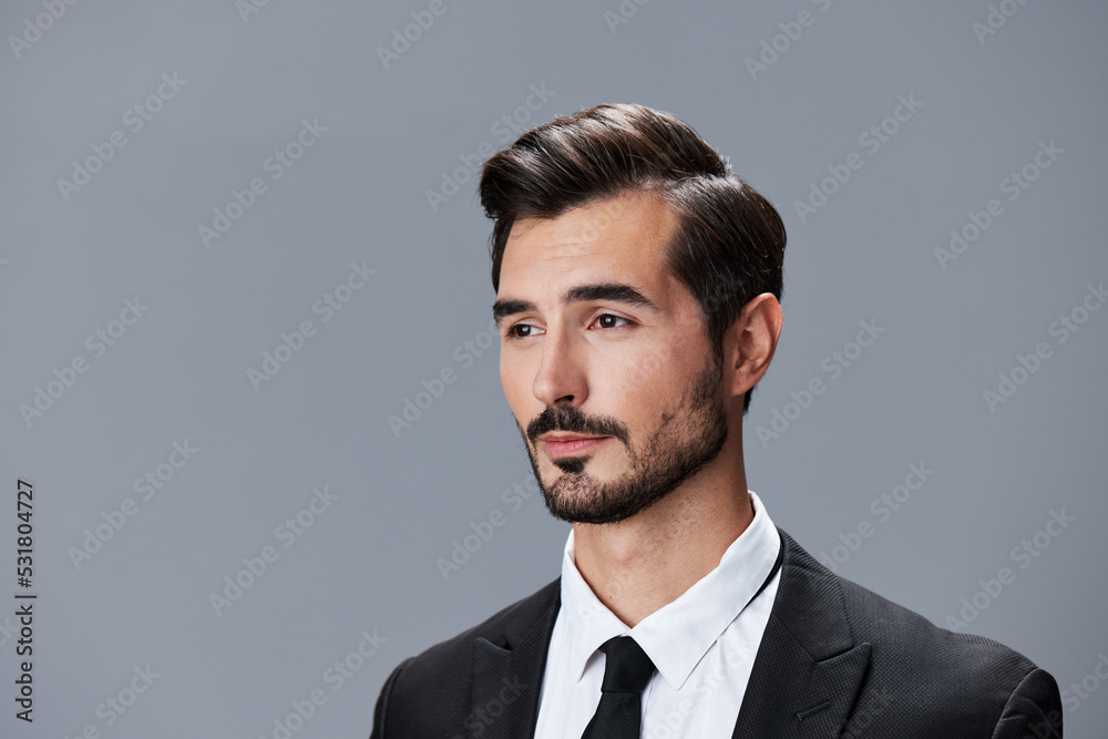 Portrait of a business man in a stylish suit with tie beautiful face on a gray isolated background. Business concept young businessman startup copy space Portrait of a business man in a stylish suit with tie beautiful face on a gray isolated background. Business concept young businessman startup copy space