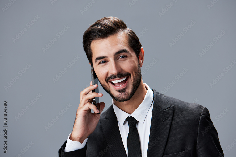 Portrait of business man with phone conversation and smile with teeth on gray background in business suit. Business portrait of a stylish man copy space Portrait of business man with phone conversation and smile with teeth on gray background in business suit. Business portrait of a stylish man copy space
