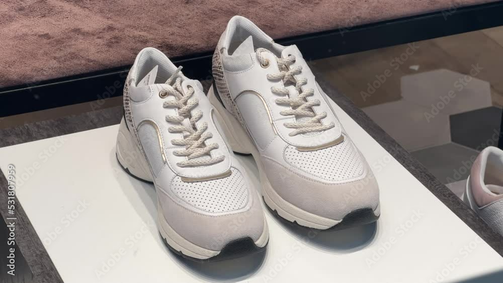 White casual sneakers with mesh stand in the window of a shoe store White casual sneakers with mesh stand in the window of a shoe store