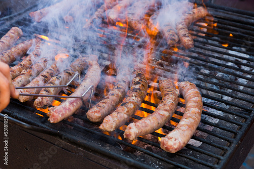 Delicious outdoor eating. Appetizing sausages grilling on portable bbq..