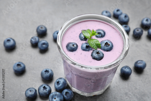 Glass of blueberry smoothie with mint and fresh berries on grey table