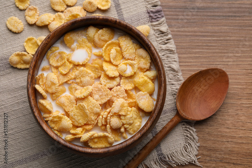 Foto Tasty cornflakes with milk in bowl served on wooden table, flat lay