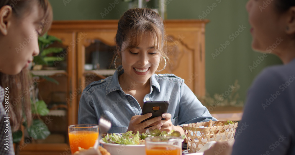 Asia young smart casual girl group friend sit at indoor coffee shop table enjoy laugh fun eat food drink lunch meal party at cafe. Relax look read e-mail text, money trade or post IG reel story app.
