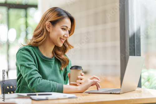 Attractive pretty asian business woman working on laptop at workstation office workplace.