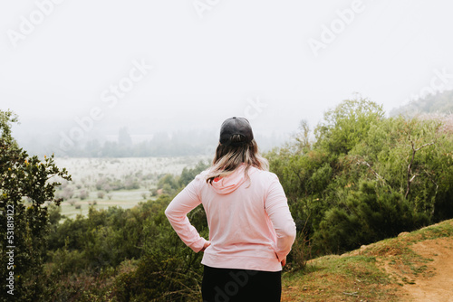 Unrecognizable latin plus size woman, climbing a hill and hiking in a beautiful landscape.