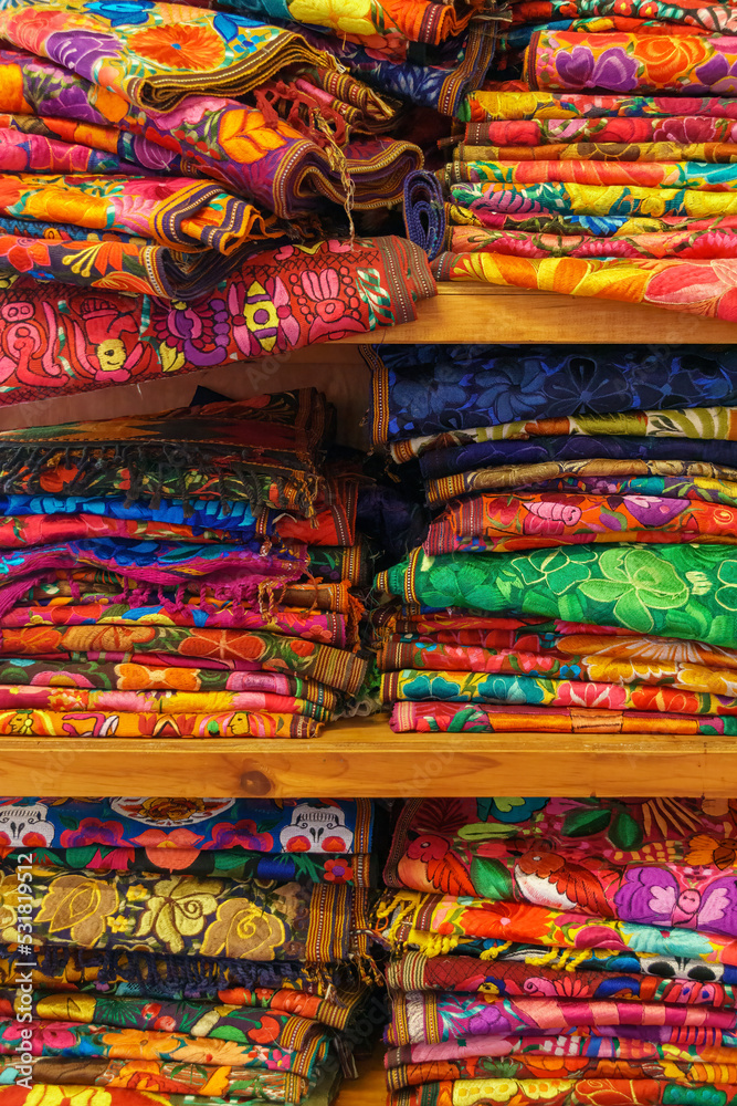 Brightly colored handwoven textiles stacked on a shelf in Merida, Mexico