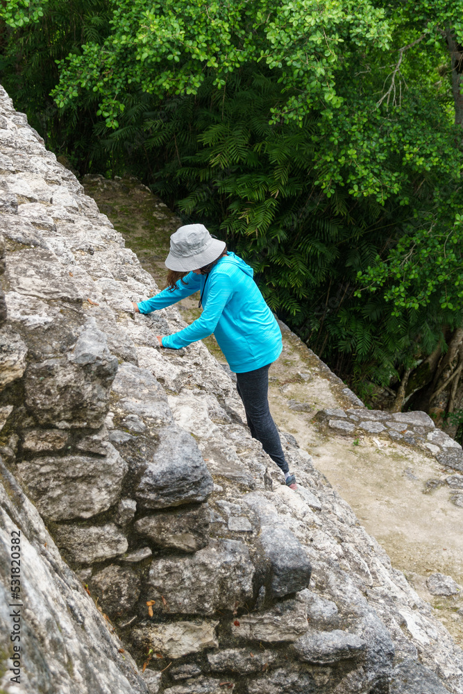 Child with an adventure hat climbs the almost vertical Mayan stone steps in Calakmul, Mexico Child with an adventure hat climbs the almost vertical Mayan stone steps in Calakmul, Mexico