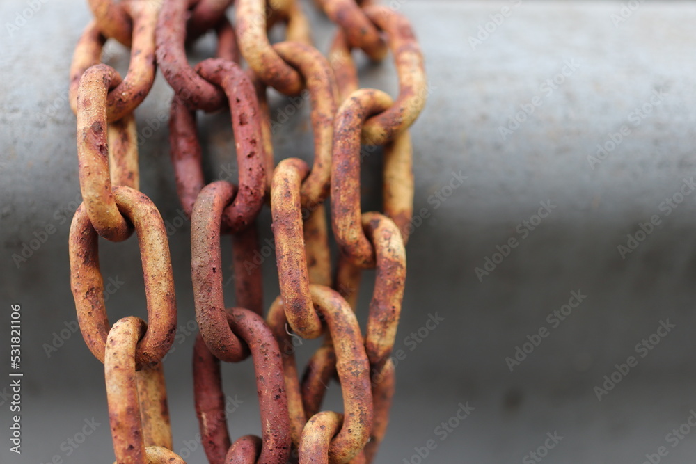 Yellow and brown rust chains wrapped around metal car guard rail Yellow and brown rust chains wrapped around metal car guard rail