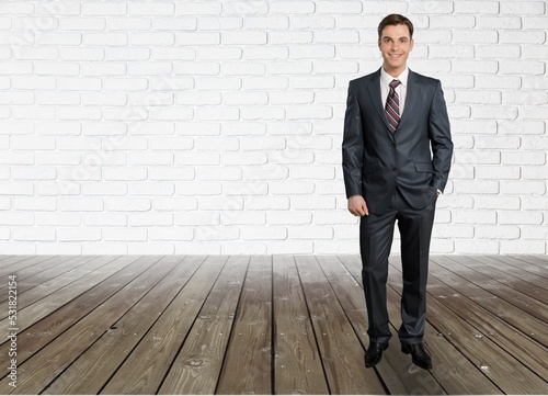 Young businessman standing in suit and posing on background, © BillionPhotos.com