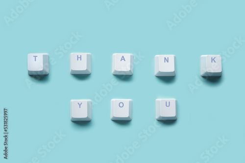 Word THANK YOU written on computer keyboard keys isolated on a turquoise