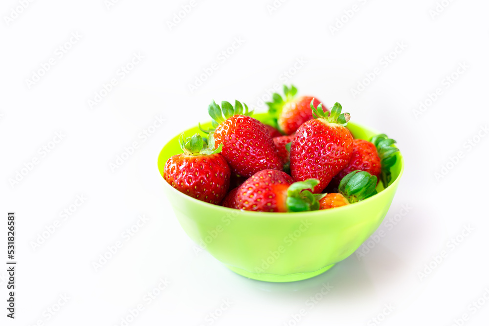Green bowl on a white surface full of beautiful strawberries. Green bowl on a white surface full of beautiful strawberries.