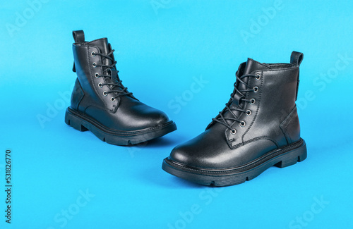 A pair of high leather boots on a bright blue background. © kvladimirv