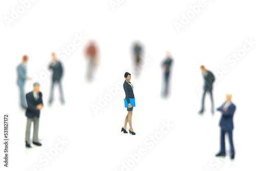 Miniature people toy figure photography. Women empowerment concept. A businesswoman standing in the middle of male people crowd. Isolated on white background