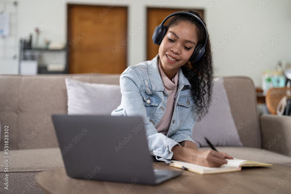 mixed race woman wearing headphones watching webinar write notes study online with online teacher, african female student learning language computer course on laptop listen translate lecture mixed race woman wearing headphones watching webinar write notes study online with online teacher, african female student learning language computer course on laptop listen translate lecture