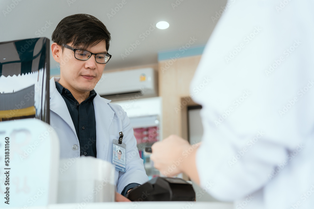 Pharmacist Chayong standing and talking to the patient Buying medicines with a credit card online spending Pharmacist Chayong standing and talking to the patient Buying medicines with a credit card online spending