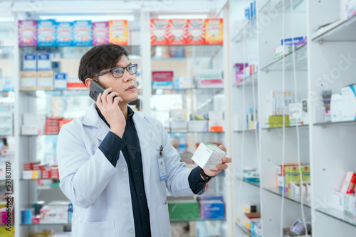 A male pharmacist checks drug stocks in a community pharmacy. use the phone to talk