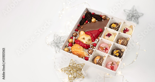 Festive Christmas set of handmade chocolates with lights and stars, on white background, banner, place for text