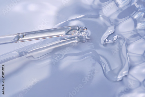 Dropper with serum or cosmetic oil on a blue background.