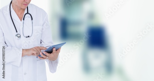 Mid section of female doctor using digital tablet in hospital 