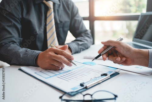 Fototapeta Naklejka Na Ścianę i Meble -  Two businessman working together to plan investment at the meeting. Close-up of businessman advisor pointing to graph and chart, analyzes financial report and profit deficit.