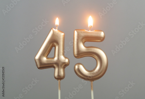 Burning gold birthday candles on gray background, number 45 photo
