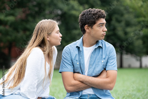 Teenager girl trying to kiss distracted boyfriend. Hispanic boy ignoring girlfriend
