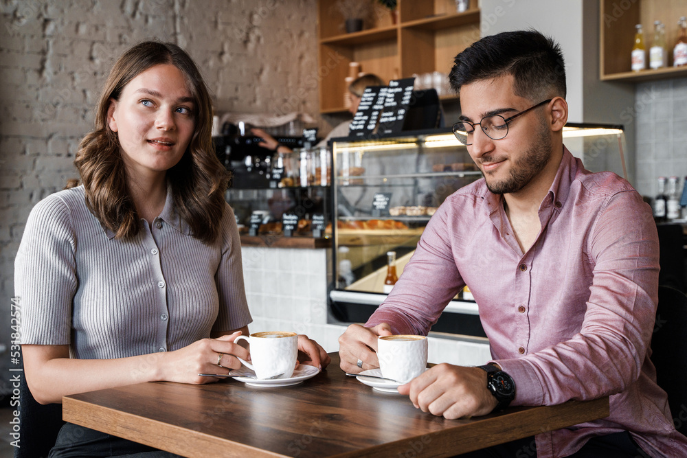 Shot of woman and man talking drinking hot coffee in coffee bar.
