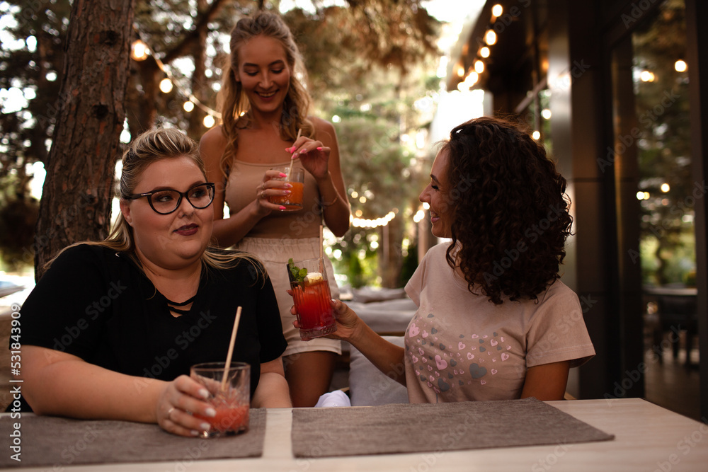Group of female friends, plus size with thin girls sit in cafe and drink the drinks.