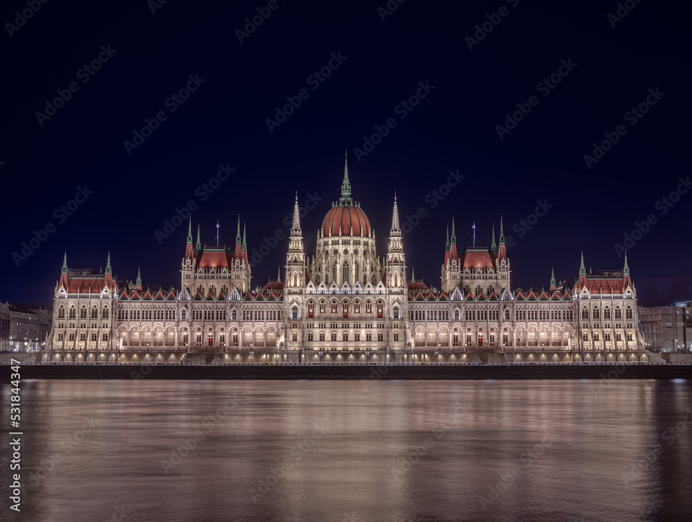 Fototapeta premium Budapest, Hungary - The beautiful illuminated Hungarian Parliament building (Orszaghaz) by night with dark blue sky and River Danube