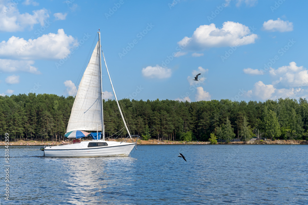 Obraz premium Pleasure yacht with white sails against the blue sky and water.