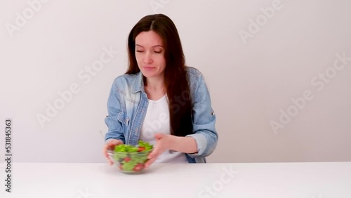 Young girl on a diet pretends to eat a salad, but while no one sees eats a piece of pizza