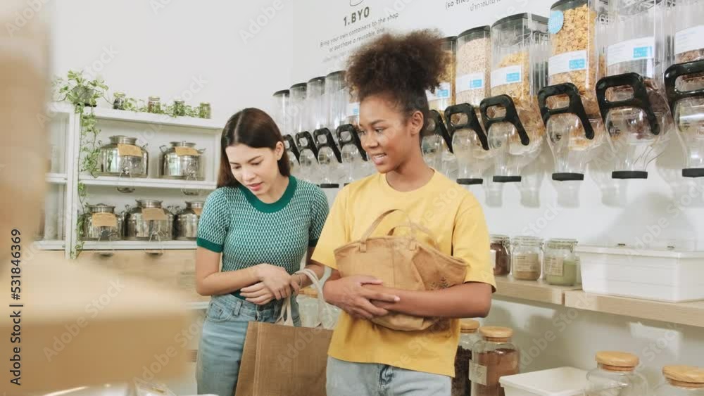Two young female customers are choosing and shopping for organic products in refill store with reusable bags, zero-waste grocery, and plastic-free, eco environment-friendly, sustainable lifestyles. Two young female customers are choosing and shopping for organic products in refill store with reusable bags, zero-waste grocery, and plastic-free, eco environment-friendly, sustainable lifestyles.
