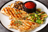 Grilled marinated healthy chicken breasts cooked on a summer barbecue and served with brussels sprouts and mushrooms close-up in a plate on the table. horizontal