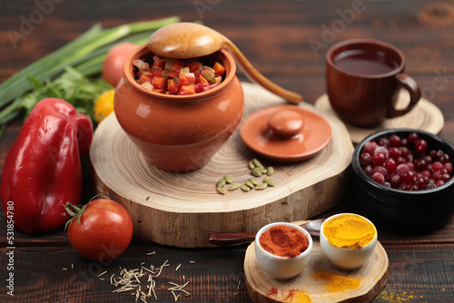 Rustic still life with a pot, wooden spoon, autumn vegetables, wooden table, dark wood. The hand holds a spoon.