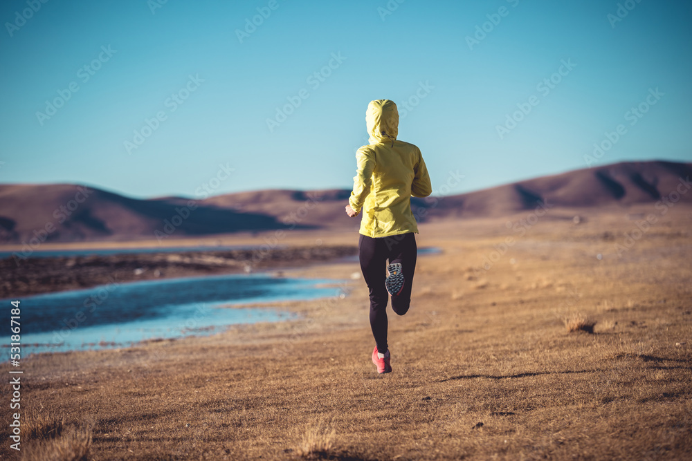 Woman trail runner cross country running on winter high altitude lakeside