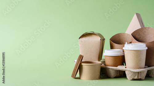 Paper disposable tableware and packaging for fast food on a green background. Free empty space on the left.