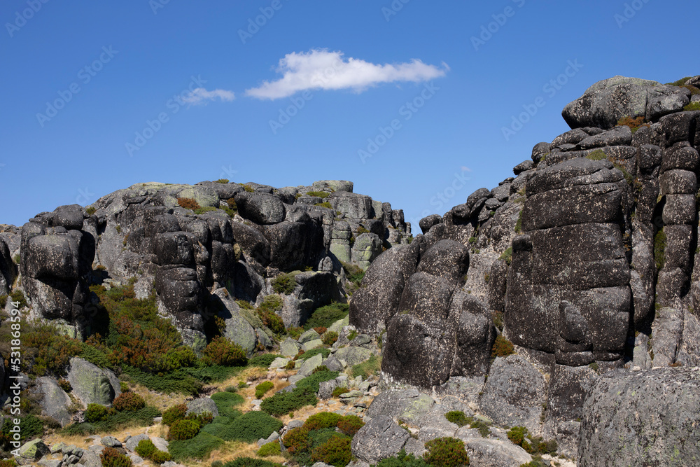 Défilé montagneux aux rochers de granit arrondis et à la végétation verte et basse dans la montagne portugaise de la Serra d'Estrela.