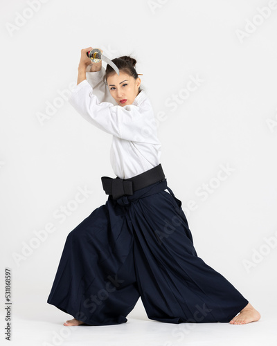 Aikido master woman in traditional samurai hakama kimono with black belt with sword, katana on white background. Healthy lifestyle and sports concept.