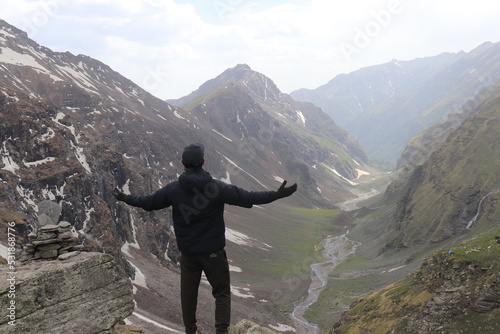 A man standing against a beautiful view in mountains and enjoying it with open arms