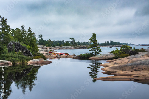 Sea kayaks on a rocky shore by reflective water in Killarney Provincial Park. Shot in the fall. Room for text.