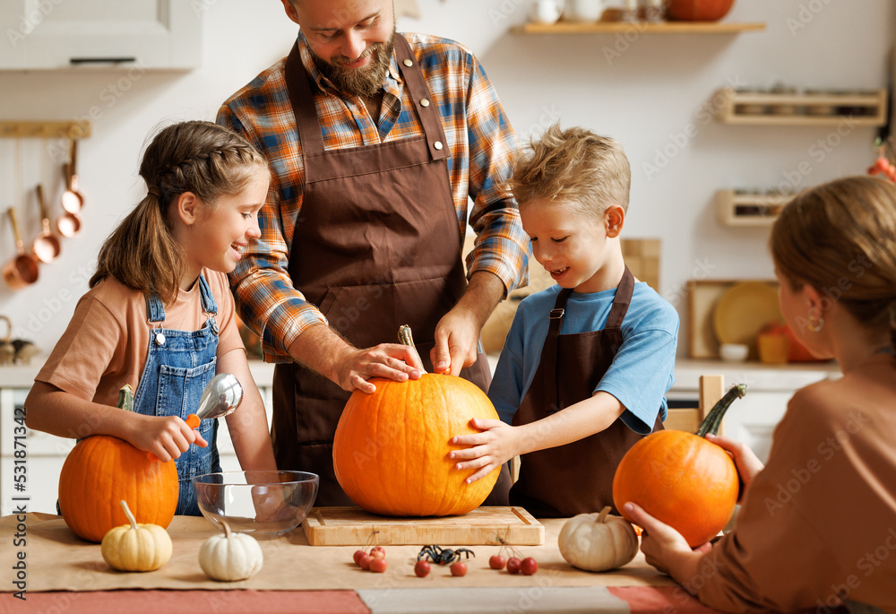 Fototapeta premium Happy family mother, father and kids to remove pulp from from pumpkin while carving jack o lantern with family