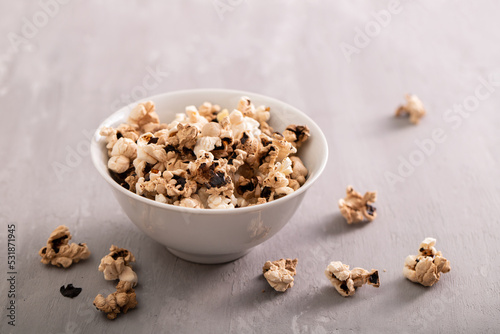 Burnt popcorn in the small white bowl on ceramic photo