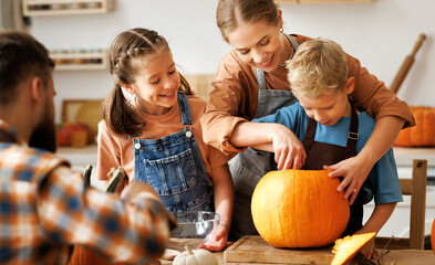 Happy family mother, father and kids  to remove pulp from from pumpkin while carving jack o lantern with family